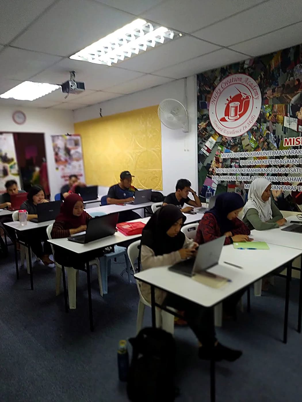 Students working on laptops in the academy's classroom