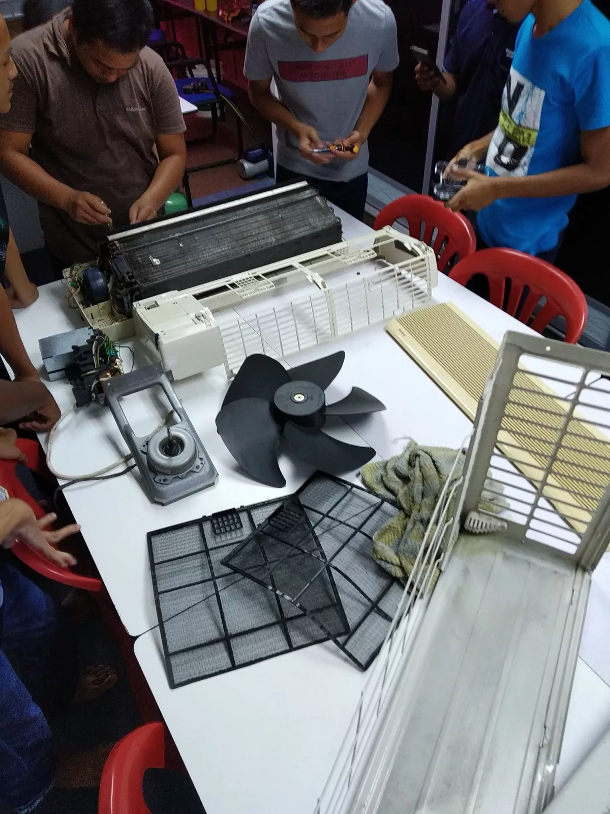 An air-conditioner stripped down to its parts across a work bench