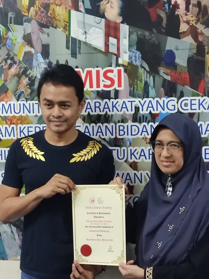 A graduate receiving a commercial tailoring certificate