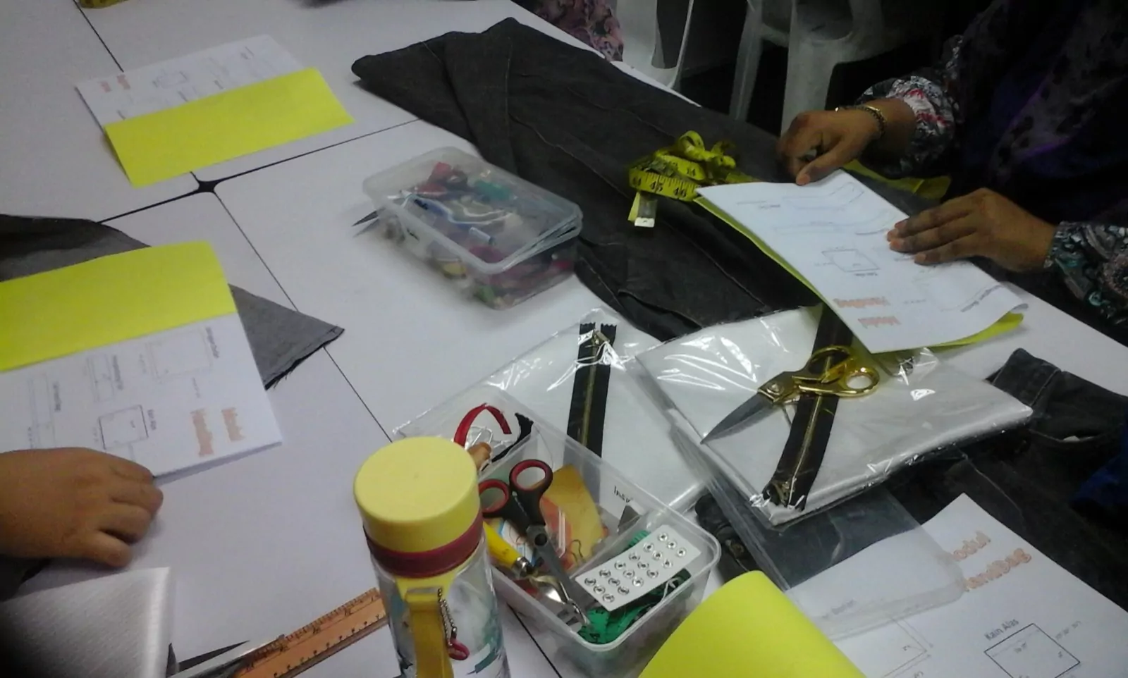 Pattern sheets, zips and sewing tools laid out across a work table