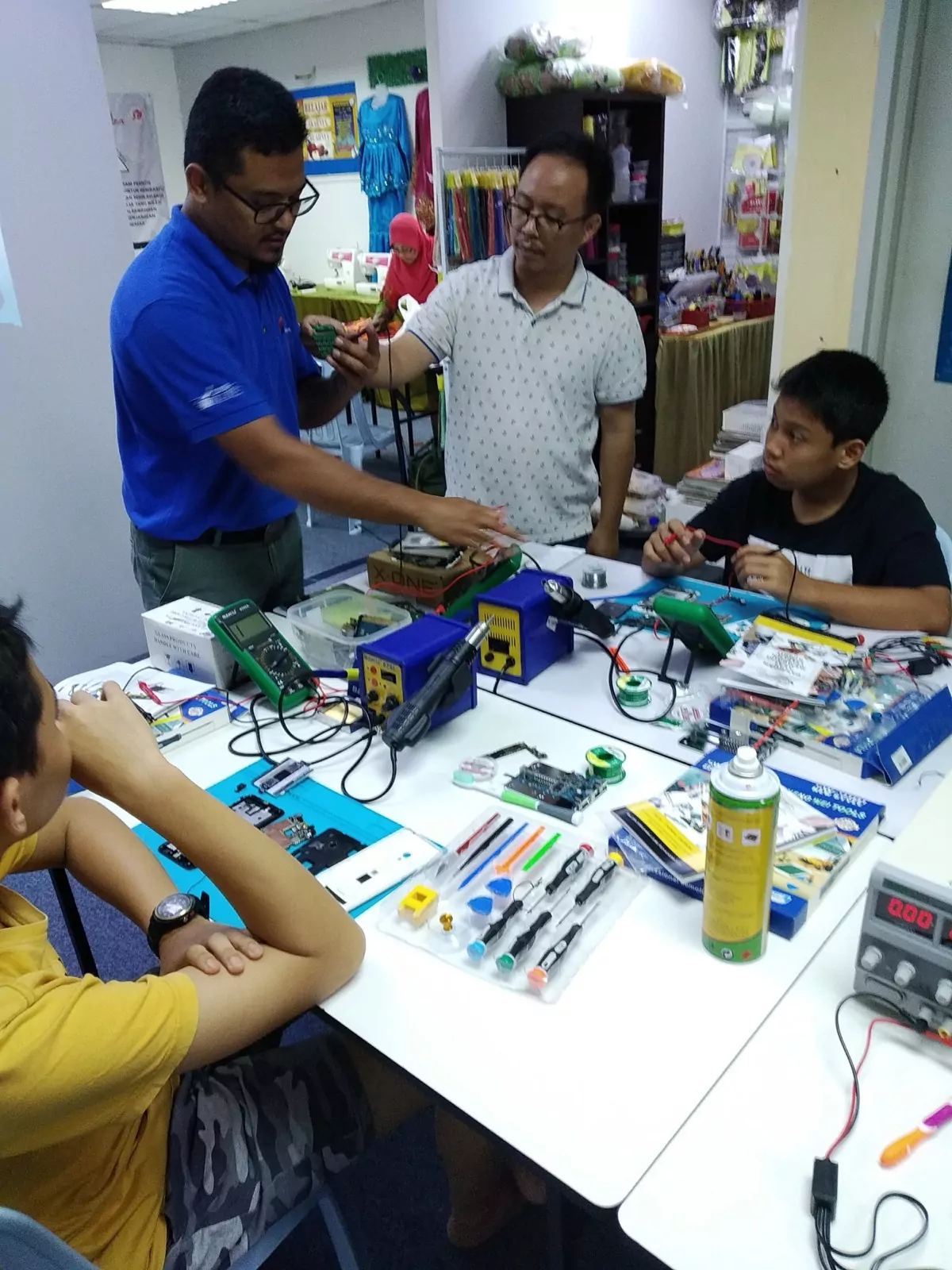 An instructor walking two students through a board-level repair