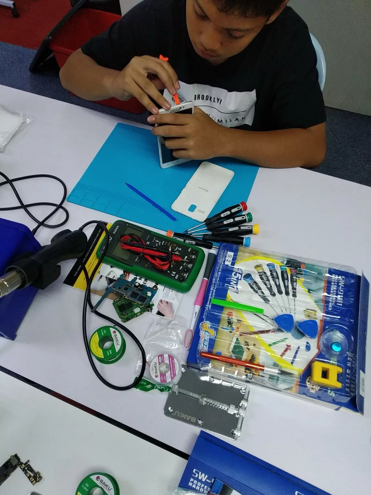 A repair toolkit and test gear laid out beside a phone