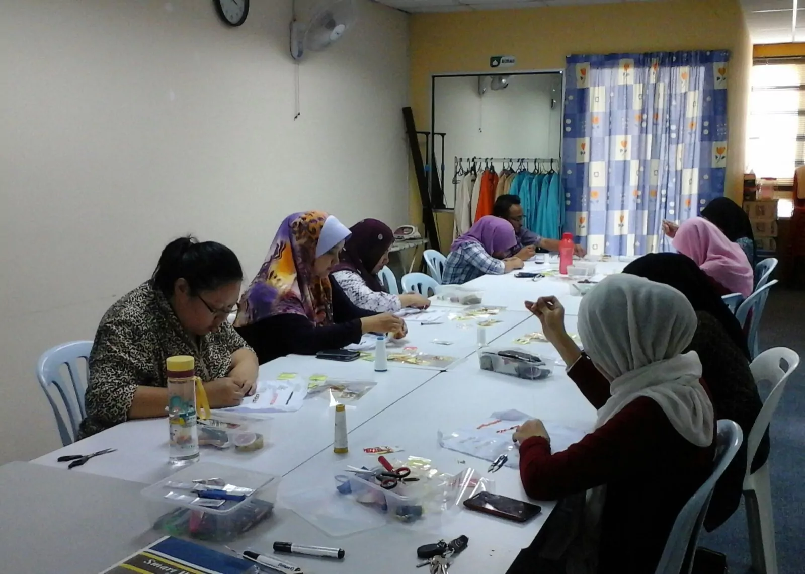 Students around a long table working on sewing and craft pieces