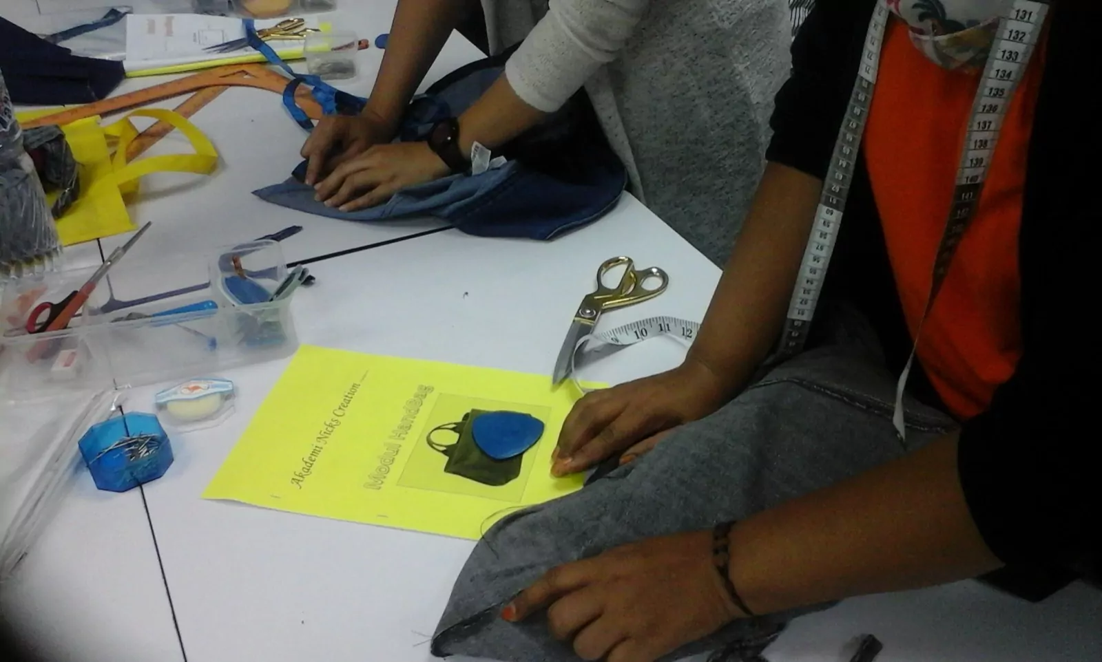 Hands working with fabric, shears and a tape measure