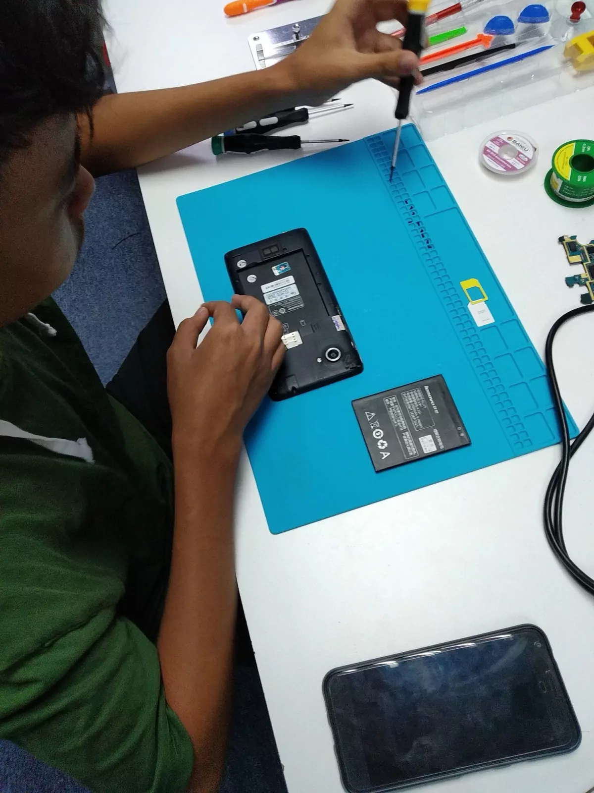 A student opening the back of a phone on a repair mat